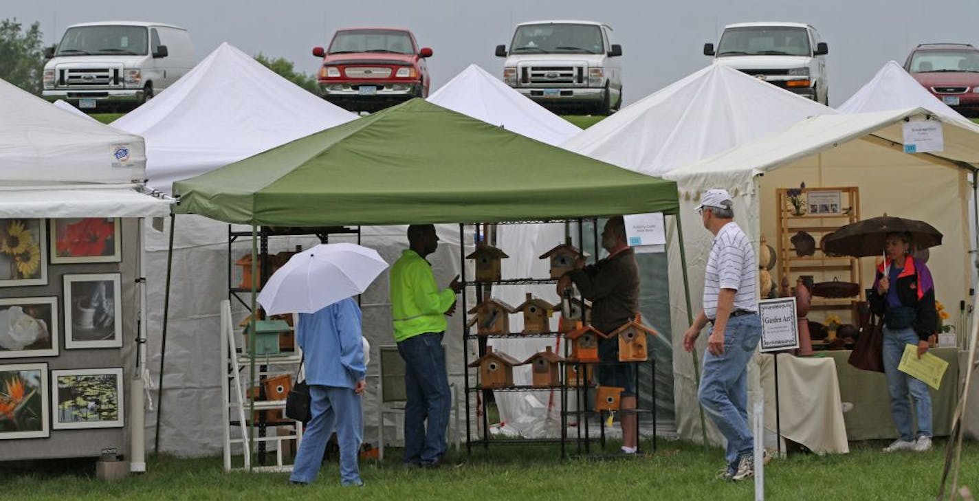 Parked cars and trucks provided an optical illusion, as people tried to stay dry at the 17th Annual Eagan Art Festival. The juried art show attracted 100 artists to the two day show and featured live music and food.