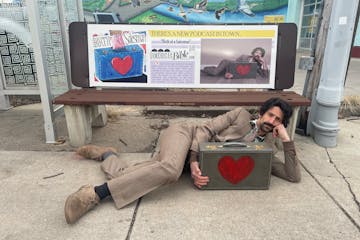 Artist Sam Robertson in front of a bus-bench advertisement about his illustrated Old Testament, a seven-year artistic project that is now the subject 