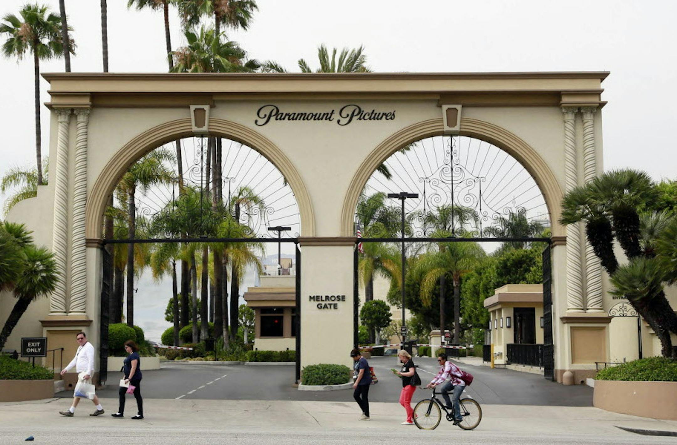 FILE - In this July 8, 2015, file photo, people pass by the main gate to Paramount Pictures on Melrose Avenue in Los Angeles. Embattled media company Viacom says it has begun a process to find a minority investor for its Paramount Pictures movie studio, heeding calls from activist investors frustrated at the Viacomís sagging performance. Shares immediately rose about 3 percent to $38.06 in midday trading Tuesday, Feb. 23, 2015.(AP Photo/Nick Ut, File)