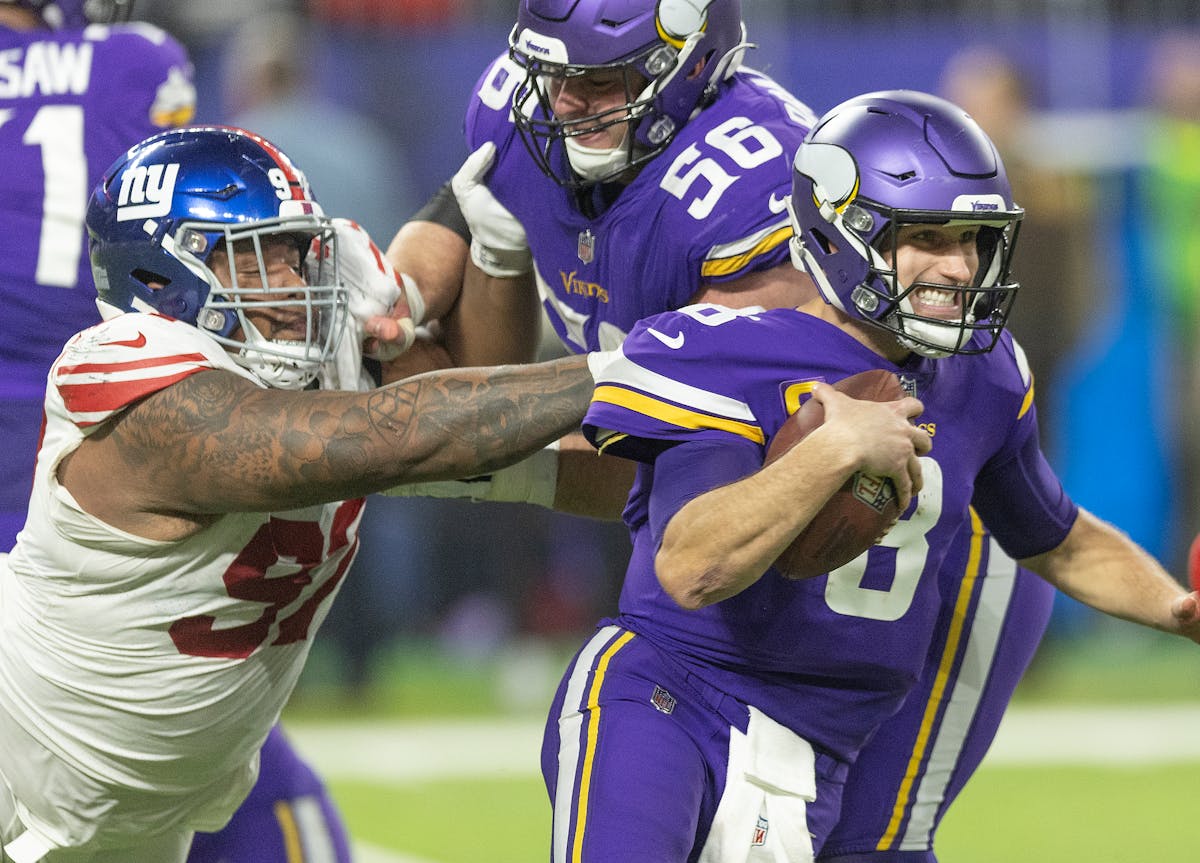 Minnesota Vikings quarterback Kirk Cousins (8) barely breaks the grasp of New York Giants defensive tackle Dexter Lawrence (97) during the fourth quar