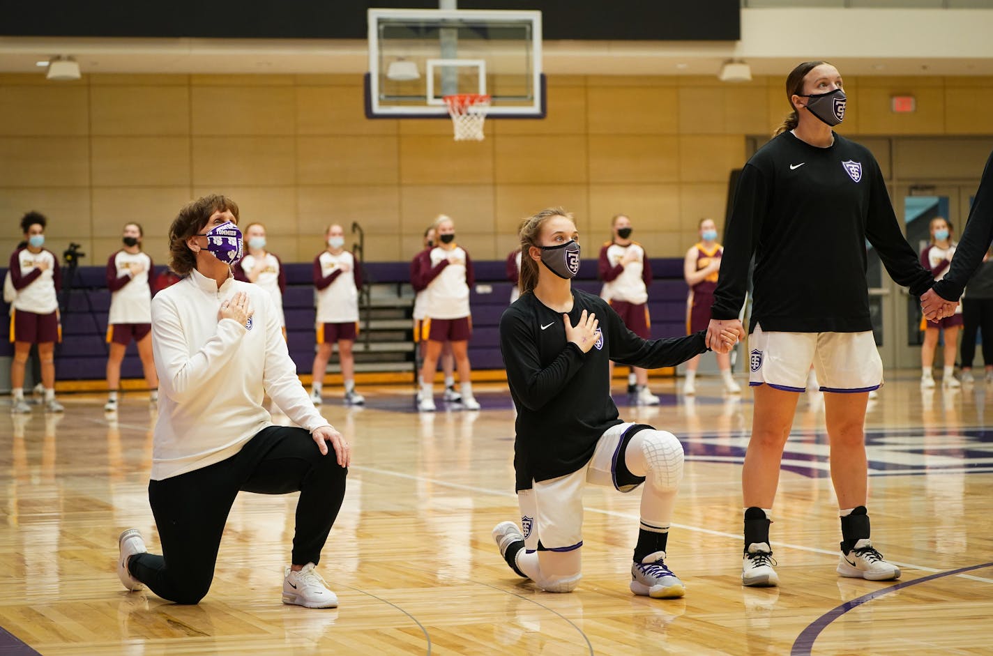 Women's basketball coach Ruth Sinn knelt alongside her St. Thomas team before the start of a game against Concordia.