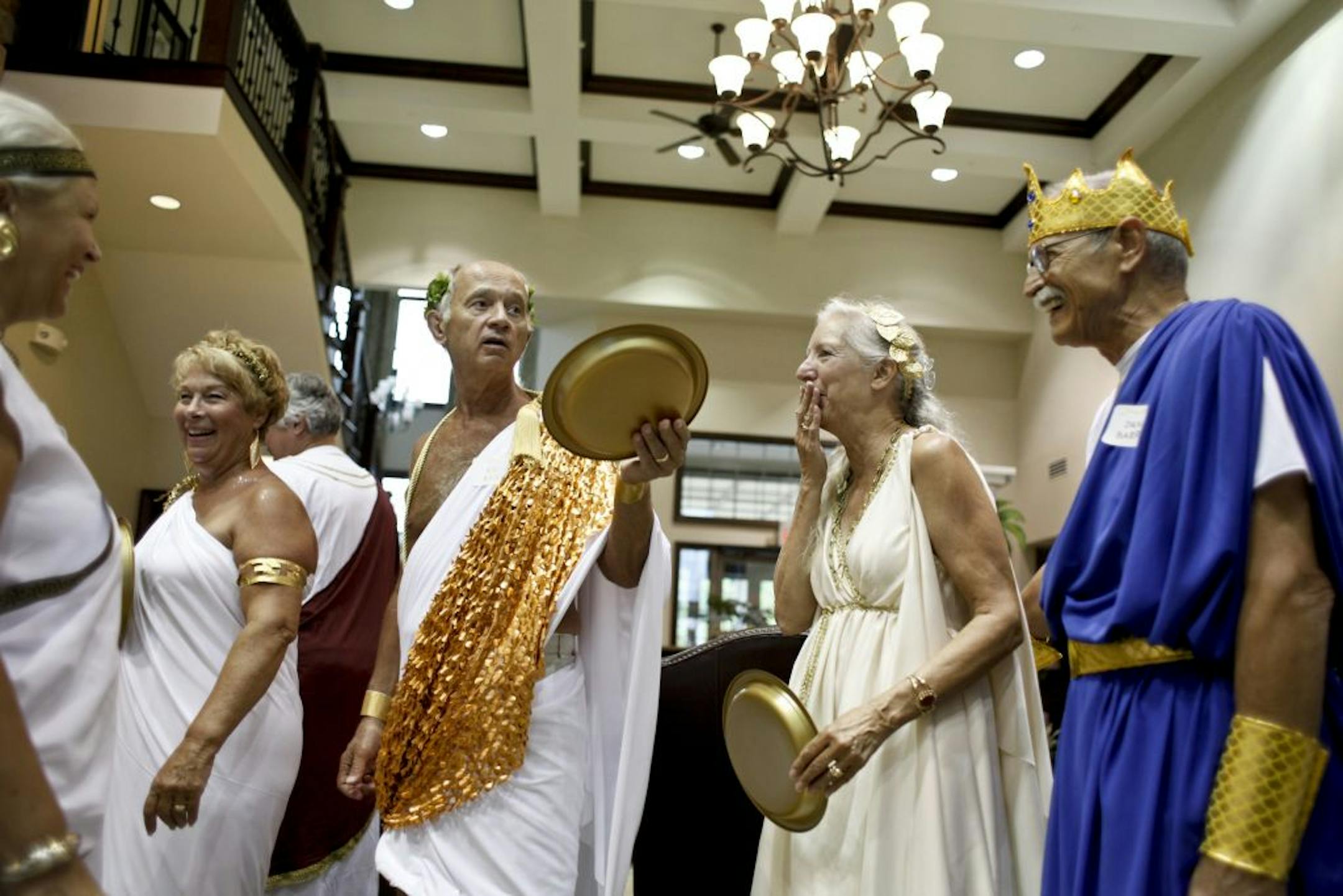 Diane and Dan Barry, right, chuckle at Ed Ayd's comment to another "Olympian" about wearing socks with sandals at the monthly themed party hosted by Marlene Gualtieri.