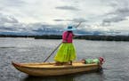 LAKE TITICACA, PERU - A young woman poles through the shallow waters of Lake Titicaca. Although the lake is nearly 1,000 feet deep, the Uros live clos