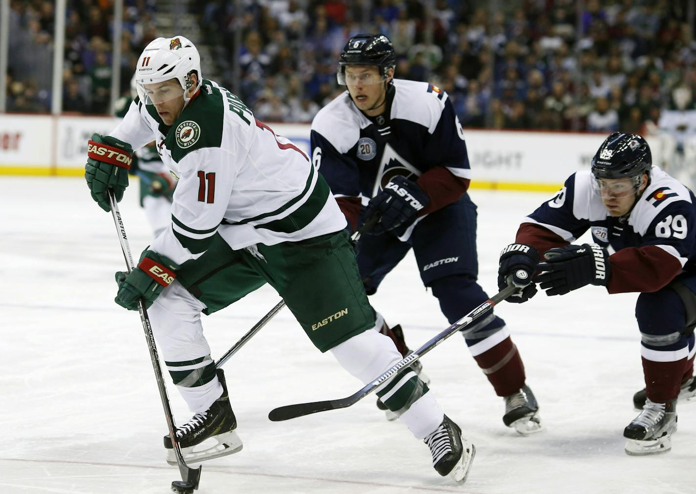 Minnesota Wild left wing Zach Parise, front, drives for a shot past Colorado Avalanche defenseman Erik Johnson, back left, and left wing Mikkel Boedker, of Denmark, in the second period of an NHL hockey game Saturday, March 26, 2016, in Denver. (AP Photo/David Zalubowski)