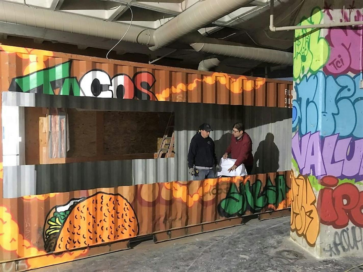 The graffiti-covered food stalls at Cargo Food Authority, shown here under construction, are built out of shipping containers.