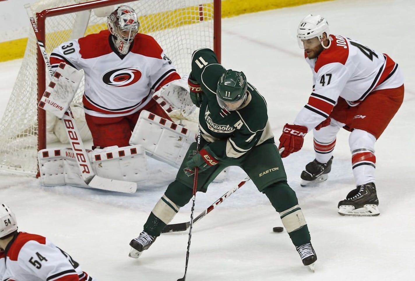 The puck gets past Minnesota Wild's Zach Parise, center, as Carolina Hurricanes' Michal Jordan, right, of the Czech Republic, and goalie Cam Ward defend in the first period of an NHL hockey game Saturday, March 19, 2016, in St. Paul, Minn.