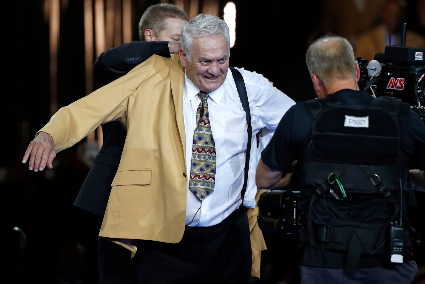 Pro Football Hall of Fame inductee Mick Tingelhoff slips on his gold jacket during the Gold Jacket Ceremony in Canton, Ohio, Thursday, Aug. 6, 2015. (AP Photo/Gene J. Puskar)