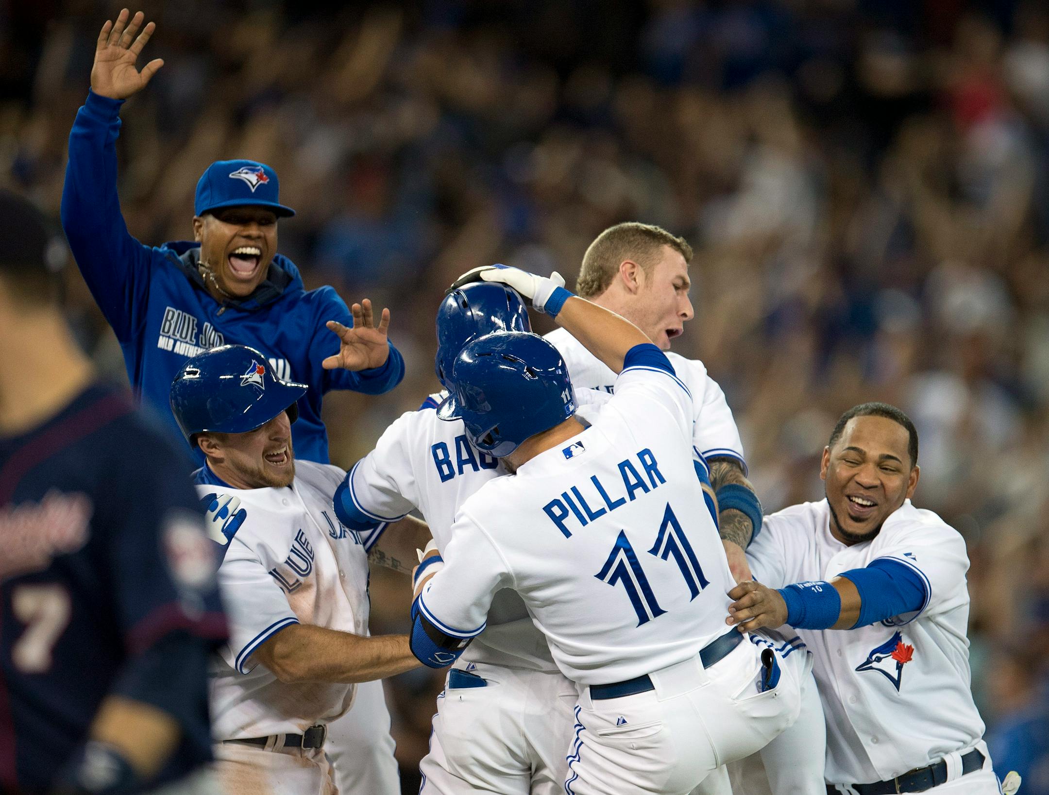 Toronto's Kevin Pillar was mobbed by teammates Erik Kratz, left, Marcus Stroman, top left, Brett Lawrie and Edwin Encarnacion, right, after hitting the game-winning to beat the Twins 5-4 on Monday night.