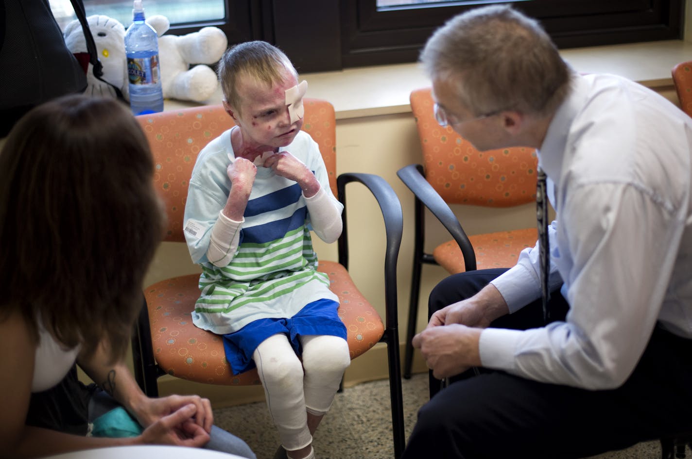 Dr. Jakub Tolar, right, director of the U of M's Stem Cell Institute, examined 7-year-old Charlie Knuth who has a rare and sometimes fatal genetic disease that causes the skin to slough off. Bone marrow transplants helped repair most of the boy's lesions, and he stands to benefit from new research spearheaded by Tolar and one of his graduate students who developed a molecular editing tool. The research illustrates the promise of an emerging field known as biomedical informatics. Charlie's mom Tr