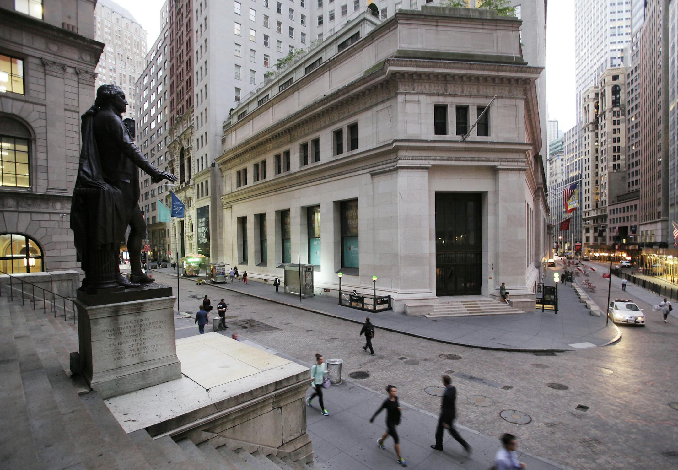 FILE - In this Oct. 8, 2014, file photo, people walk to work on Wall Street beneath a statue of George Washington, in New York. Global stock markets edged up on Monday, Sept. 18, 2017, as investors looked ahead to a U.S. Federal Reserve meeting and U.S. President Donald Trump's speech at the United Nations. (AP Photo/Mark Lennihan, File)