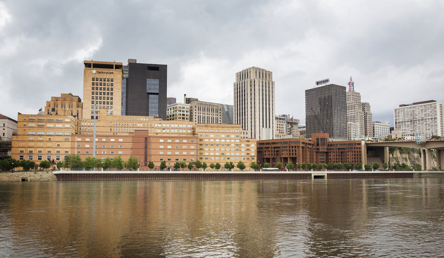 The former West Publishing building, long tan building on left, and former Ramsey County jail building, squat reddish-brown building on right, are seen from across the Mississippi River in downtown St. Paul on Friday, May 29, 2015. ] LEILA NAVIDI leila.navidi@startribune.com / BACKGROUND INFORMATION: This June, Ramsey County will begin razing the former West Publishing building and Ramsey County jail along the St. Paul's downtown river bluff to make way for a sale and new development of the area