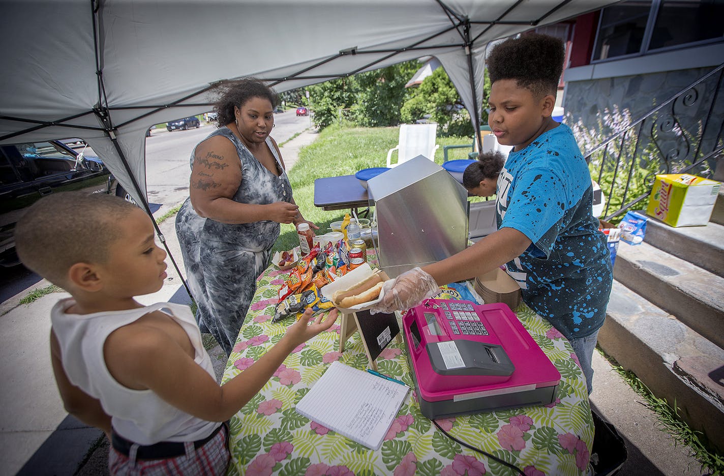 Thirteen-year-old hot dog entrepreneur Jaequan Faulkner served up a hot dog meals to Yvonne Ross and her son Drameris Ross, 7, at his hot dog stand, Monday, July 16, 2018 in Minneapolis, MN.