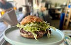 The Pão burger on the bar at Hola Arepa, topped with shreds of lettuce and just a little bit of mayo. The bun is threaded with rivers of melted chees