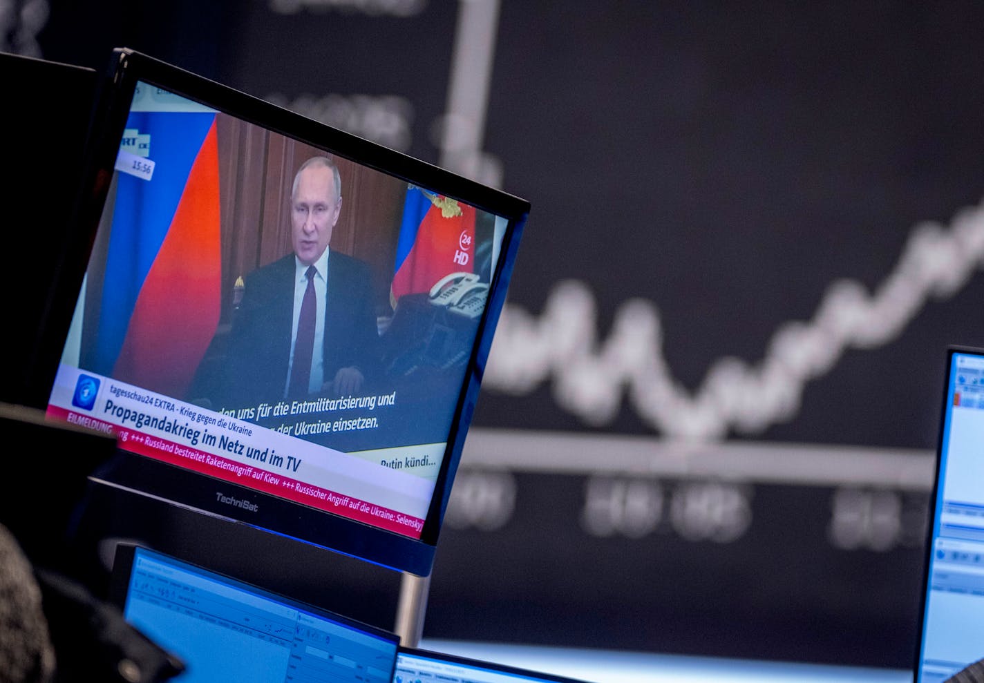 FILE - Russia's President Vladimir Putin appears on a television screen at the stock market in Frankfurt, Germany, Feb. 25, 2022. Russia is revving up its sophisticated propaganda machine as its military advances in neighboring Ukraine. Analysts who monitor propaganda and disinformation say they've seen a sharp increase in online activity linked to the Russian state in recent weeks. (AP Photo/Michael Probst, File)