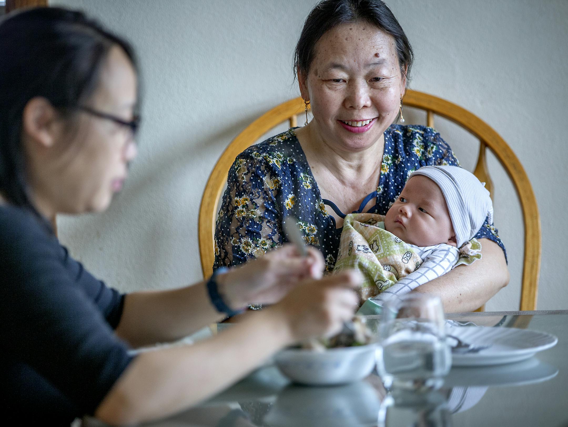 Yee Lee held her grandson Keng Xiong as her daughter, Jouapag Lee, ate the traditional Hmong Chicken Herb Soup (Thsuaj ray Qaib) she made for her, Sunday, March 31, 2019 in Little Canada, MN. The soup is made of holistic herbs including lemongrass and chicken from a local farmer. According to Lee, the soup is a traditional Hmong 30 day postpartum diet. They believe that the soup helps in recovery and improves the production of milk and helps with later-in-life health issues. ] ELIZABETH FLORES &