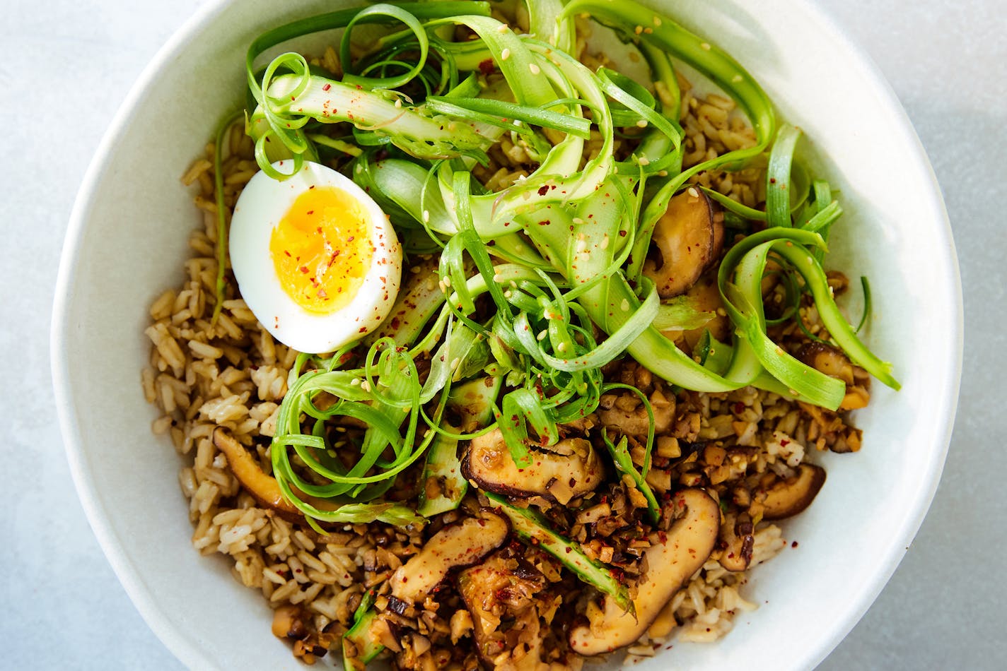 An asparagus-mushroom grain bowl in New York, May 4, 2023. Asparagus, shaved into ribbons, tops this hearty, mushroom-filled grain bowl. Food styled by Maggie Ruggiero. (Ryan Liebe/The New York Times)