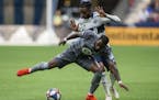 Vancouver Whitecaps' Alhassane Bangoura, rear, plays the ball against Minnesota United's Romain Metanire during the second half of an MLS soccer match
