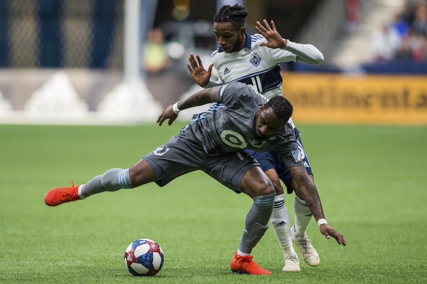 Vancouver Whitecaps' Alhassane Bangoura, rear, plays the ball against Minnesota United's Romain Metanire during the second half of an MLS soccer match Saturday, March 2, 2019, in Vancouver, British Columbia. (Ben Nelms/The Canadian Press via AP)