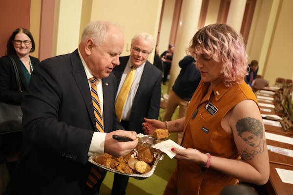 Gov. Tim Walz serves Rep. Leigh Finke, DFL-St. Paul, a pumpkin blondie bar ahead of the first day of session Tuesday, Jan. 3 in the House chamber.