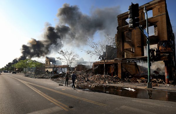 People surveyed the damage along Lake St. near S. 27th Ave. as a fire burned to the east May 30, 2020, in Minneapolis.