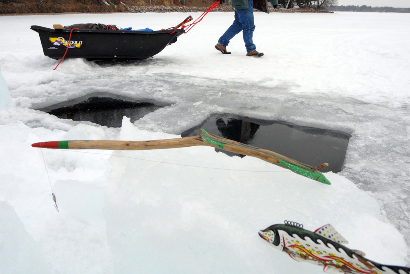 Having ended a morning on the ice, Kirk Schnitker pulls a sled of equipment toward his truck. In the foreground is one of his handmade jigging sticks, and a decoy.