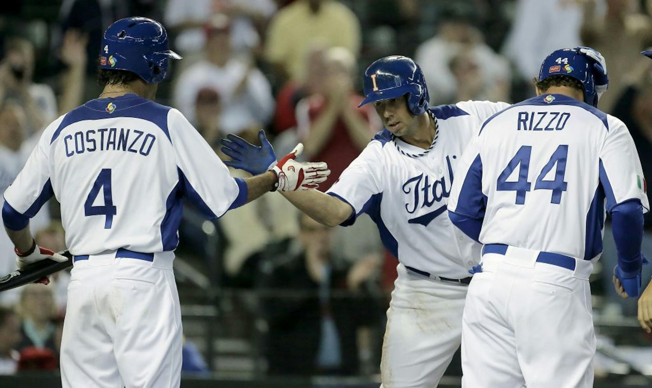 Italy's Chris Colabello, center, celebrates with Mike Costanzo (4) after hitting a 3-run home run during the third inning of a World Baseball Classic game