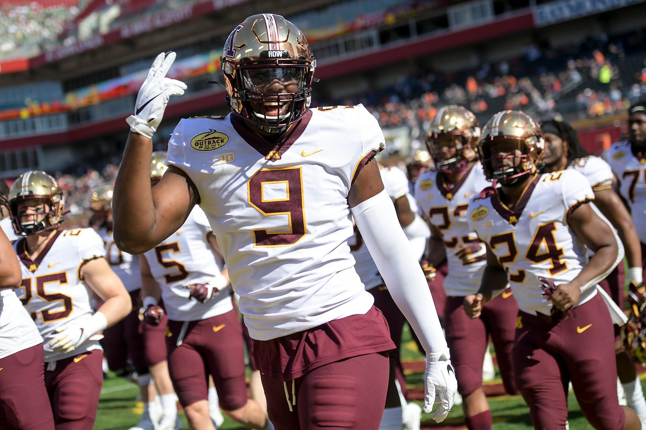 Minnesota Gophers defensive lineman Esezi Otomewo (9) gestured to fans as he ran off the field with teammates before Wednesday's game against the Auburn Tigers.