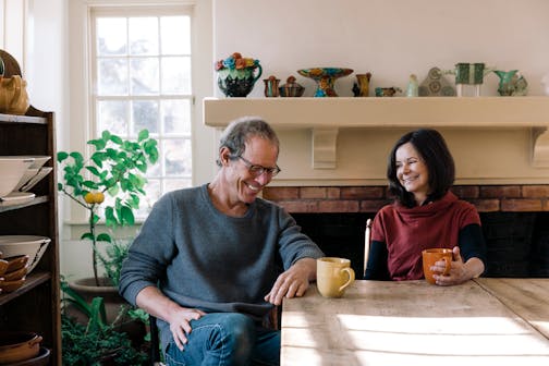 photo of authors/spouses Tony Horwitz and Geraldine Brooks, seated at a table in front of a fireplace