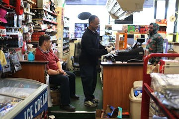 Phoenix Market manager Tarig Mohamed, center, makes change for a customer, as friend and customer Mustafa Naffa, left, looks on at the Dayton's Bluff 