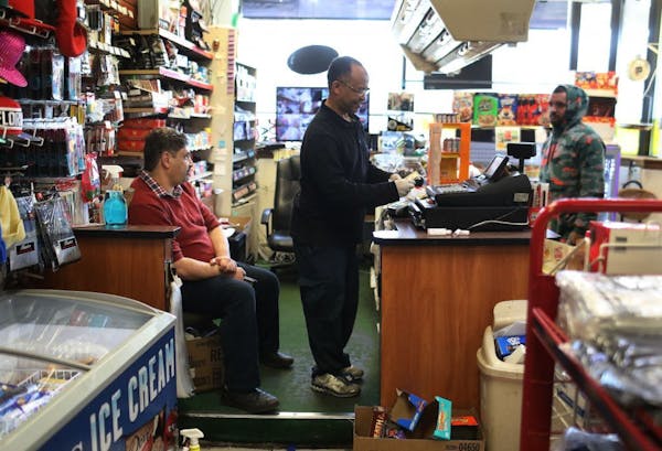 Phoenix Market manager Tarig Mohamed, center, makes change for a customer, as friend and customer Mustafa Naffa, left, looks on at the Dayton's Bluff 