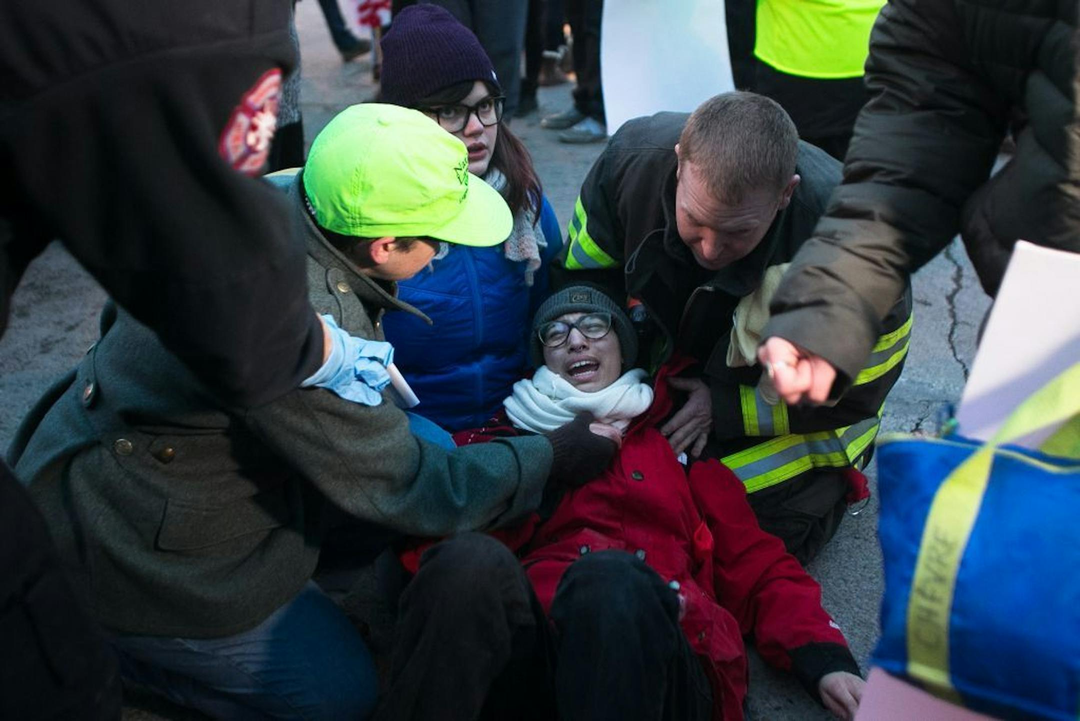 Demonstrators and first responders tend to the injuries of a woman who was hit by a car which plowed through protestors in the intersection of East Lake Street and Minnehaha.