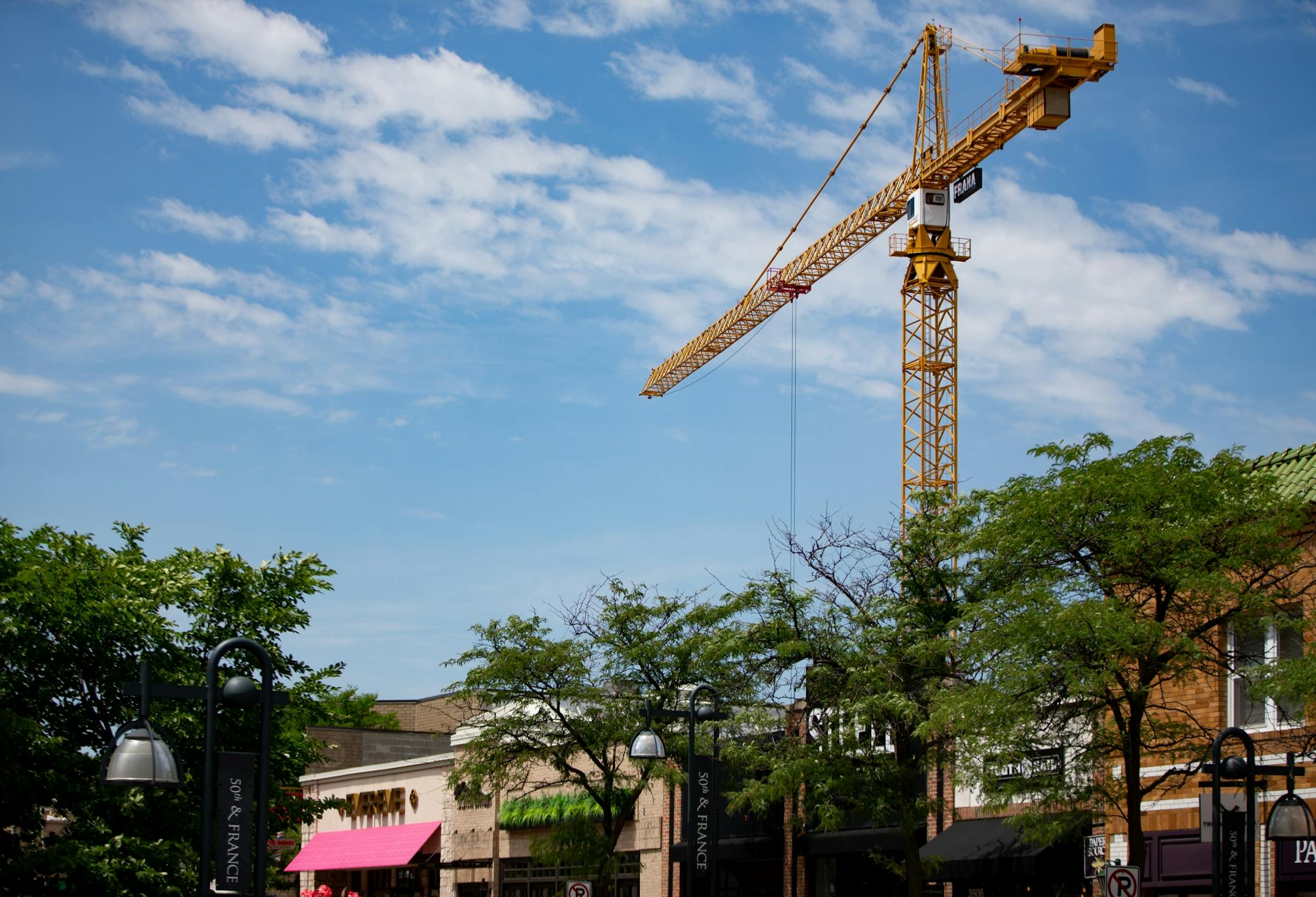 A crane aiding in the construction of a new parking ramp looms over small shops in the area.