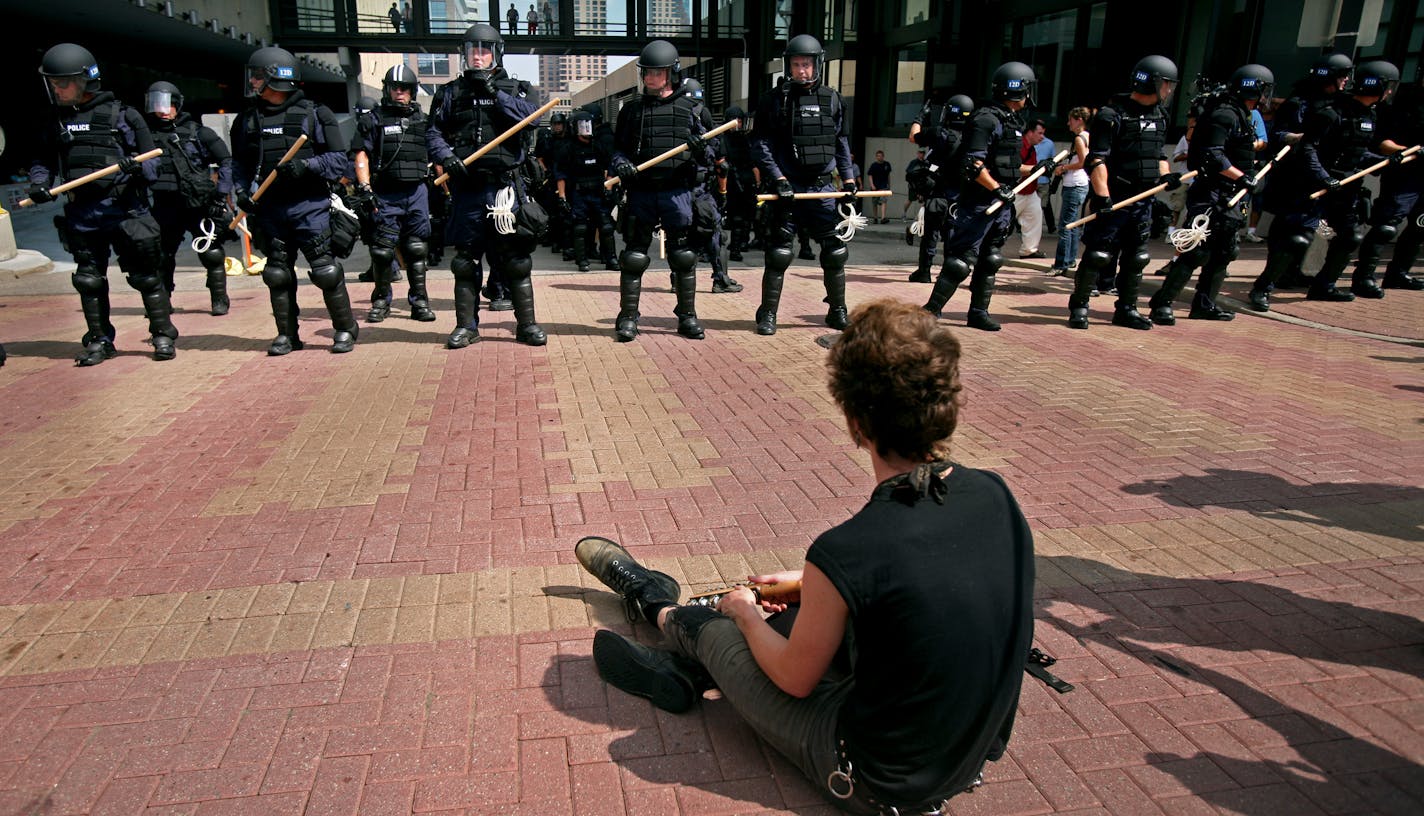 A lone protester faced a line of police in downtown St. Paul on Monday. Some protesters have said the full riot gear and aggressive attitude did not help keep the peace.