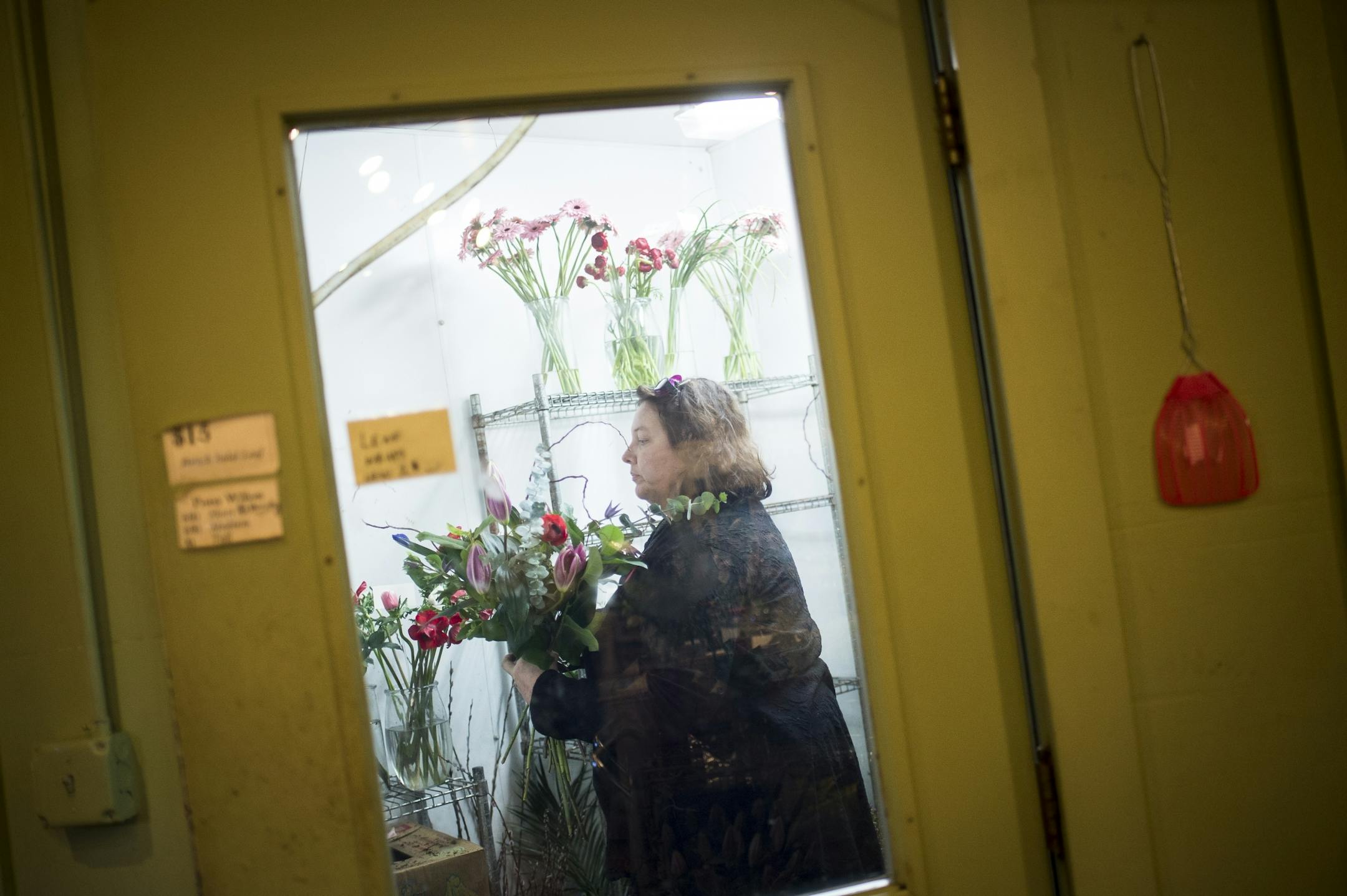 Erika Friesen, a florist at Fleur de Lis Flowers, grabbed a handful of fresh flowers while making an arrangement Friday. Friesen has been an employee of Fleur de Lis Flowers in St. Paul on and off for about ten years.