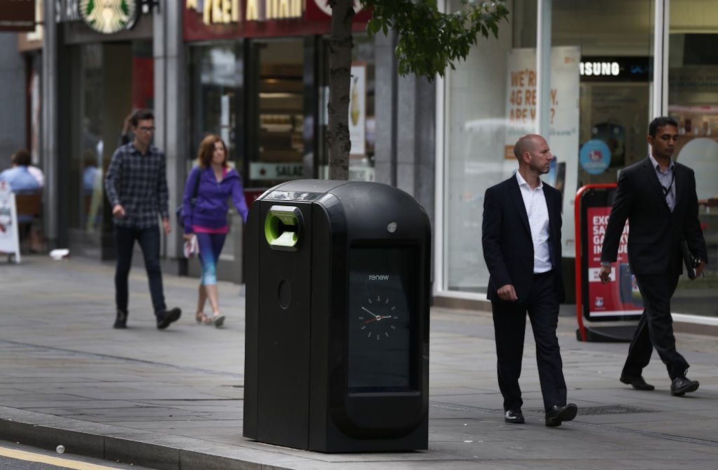 People walk past a trash bin in central London, Monday, Aug. 12, 2013. Officials say that an advertising firm must immediately stop using its network of high-tech trash cans, like this one, to track people walking through London's financial district.