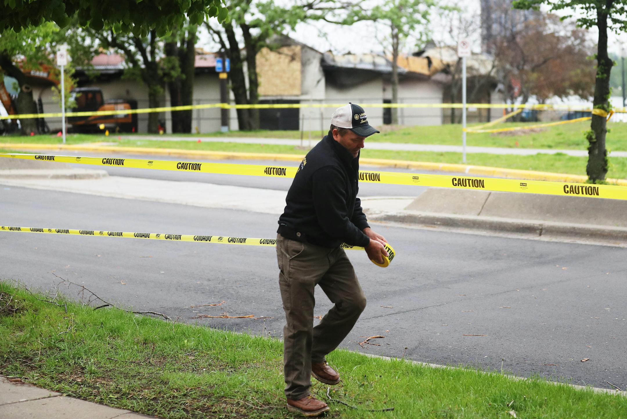 Greg Palm of Lindstrom Restoration of Plymouth, places construction tape near the pavilion at Bde Maka Ska/Lake Calhoun that housed Lola on the Lake, recently destroyed by fire, before demolition began Tuesday, May 28, 2019, in Minneapolis.