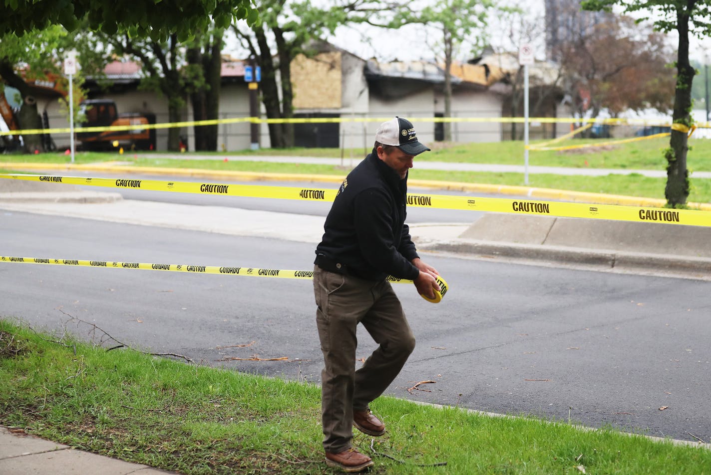 Greg Palm of Lindstrom Restoration of Plymouth, places construction tape near the pavilion at Bde Maka Ska/Lake Calhoun that housed Lola on the Lake, recently destroyed by fire, before demolition began Tuesday, May 28, 2019, in Minneapolis.