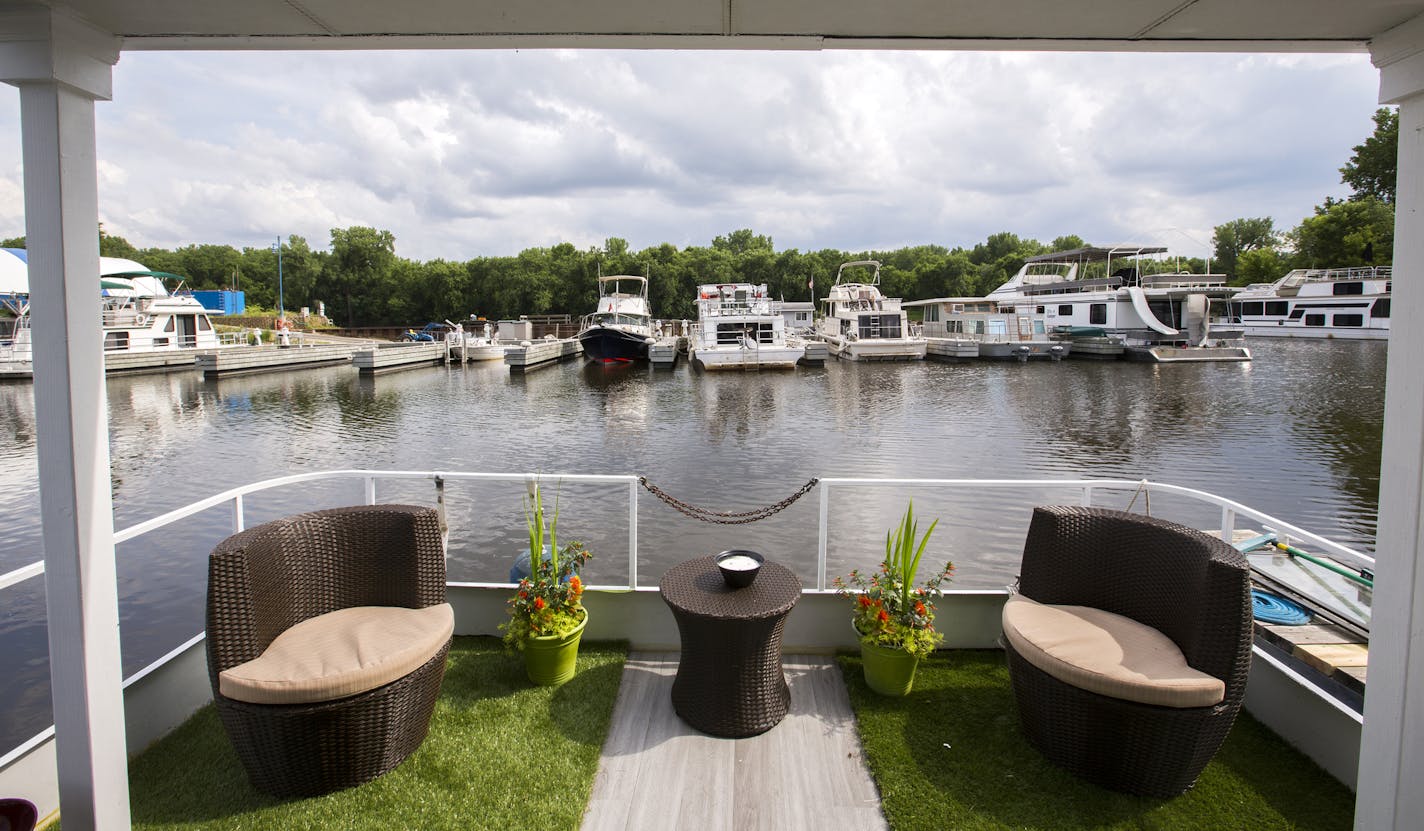 Van&#x2019;s &#x201c;patio,&#x201d; top photo, overlooks the water and the marina. She added a second floor and vinyl siding to her houseboat, above, which is docked on the Mississippi River in St. Paul.