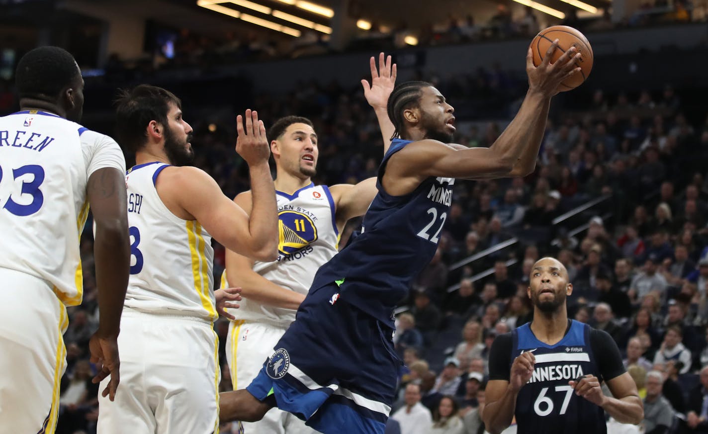 Andrew Wiggins glided between Golden State guard Klay Thompson, right, and forward Omri Casspi in the first half of Sunday's Wolves victory and stayed on the attack all night.