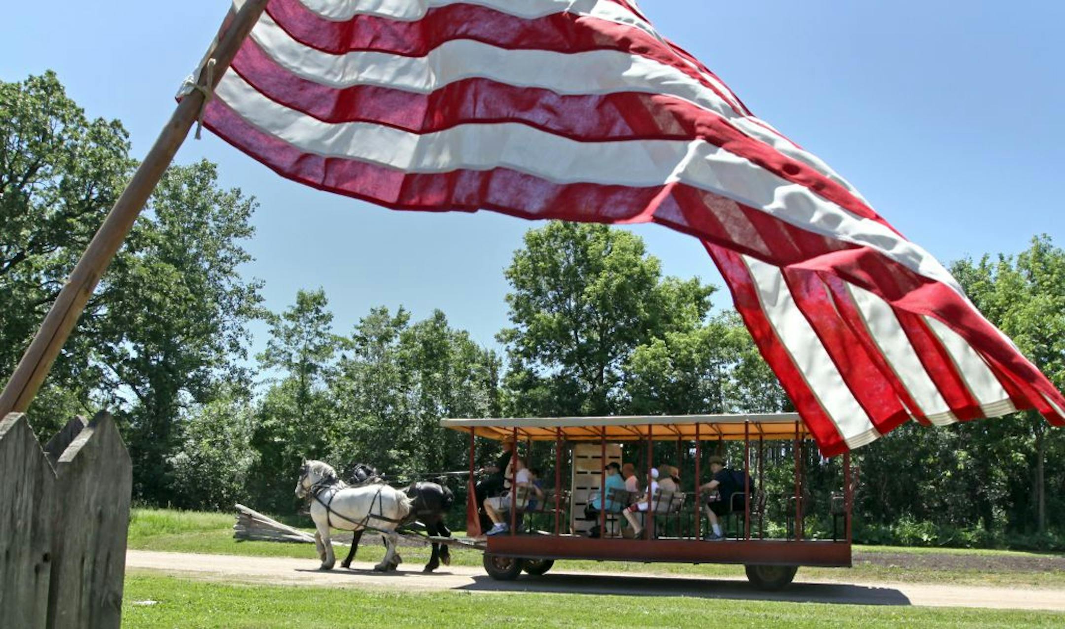 An American flag framed a Percheron horse-drawn trolley as it passed by historic buildings at "The Landing" during it's Memorial Day Encampment celebration. The memorial weekend activities include drills by the 5th Minnesota Civil War reenactors, trolley rides, and 1800's craft demonstrations. On Monday activities include Wilderness Inquiry canoe rides, music at the gazebo, a period baseball game, memorial day ceremony and drills by the 5th Minnesota Civil War reenactors.