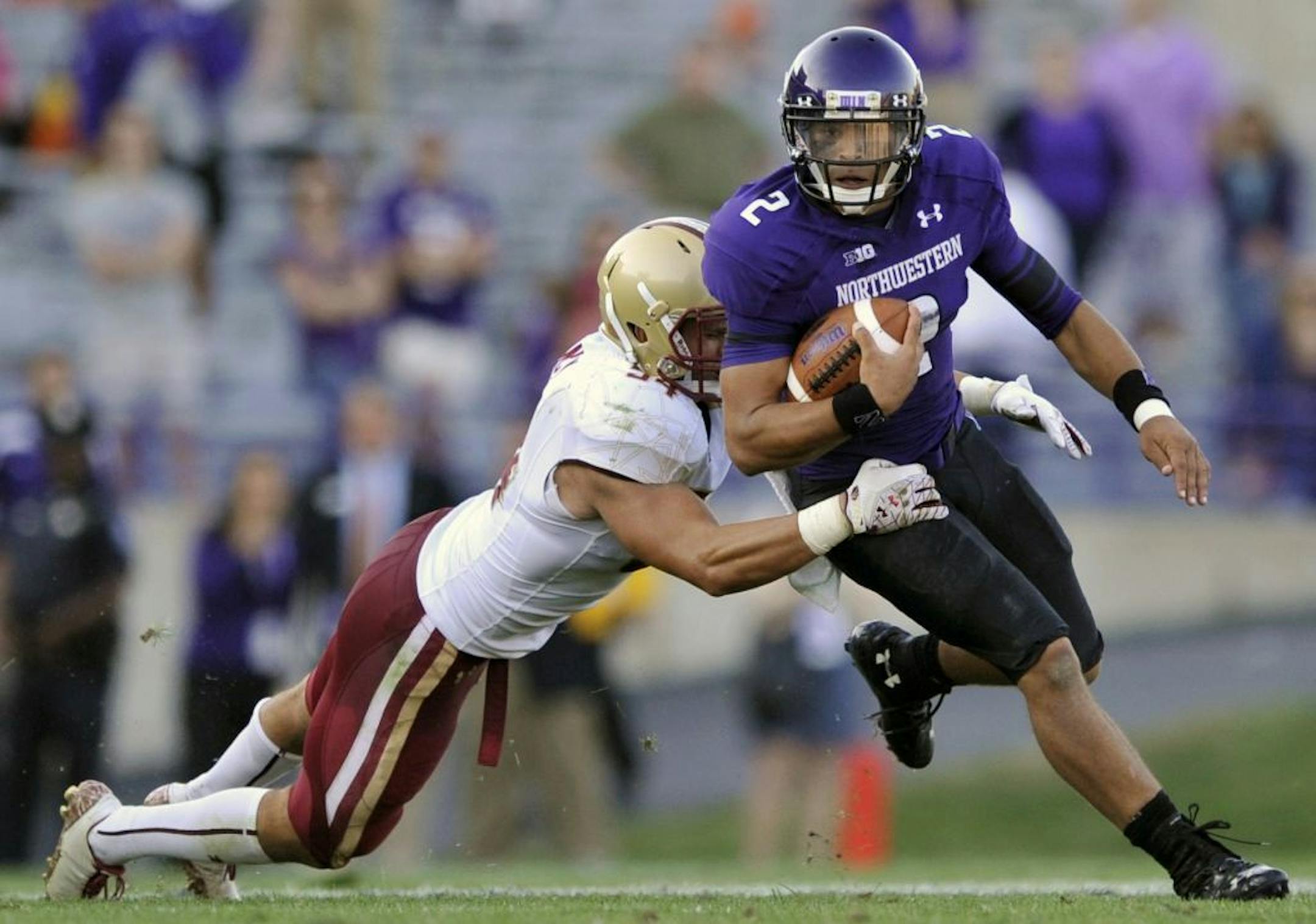 Northwestern quarterback Kain Colter rushes while being tackled by Boston College's Nick Clancy.
