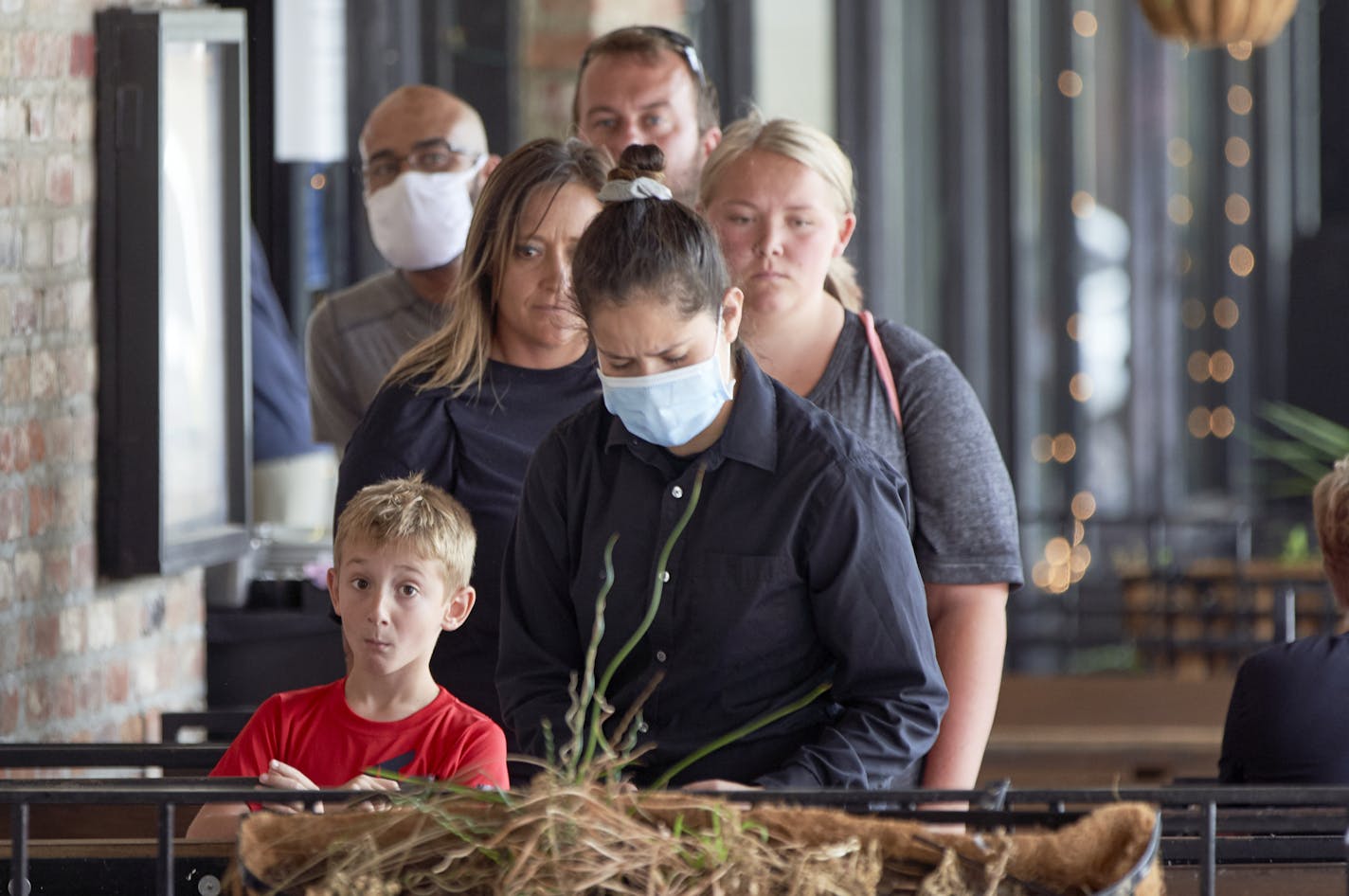 Diners wait for their waitress, center with face mask, to prepare their table at a restaurant in downtown Omaha, Neb., Friday, Aug. 7, 2020. (AP Photo/Nati Harnik)