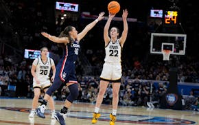 Iowa guard Caitlin Clark (22) shoots a three-point basket over UConn guard Nika Muhl (10) during the second half of a Final Four college basketball ga