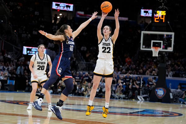 Iowa guard Caitlin Clark (22) shoots a three-point basket over UConn guard Nika Muhl (10) during the second half of a Final Four college basketball ga