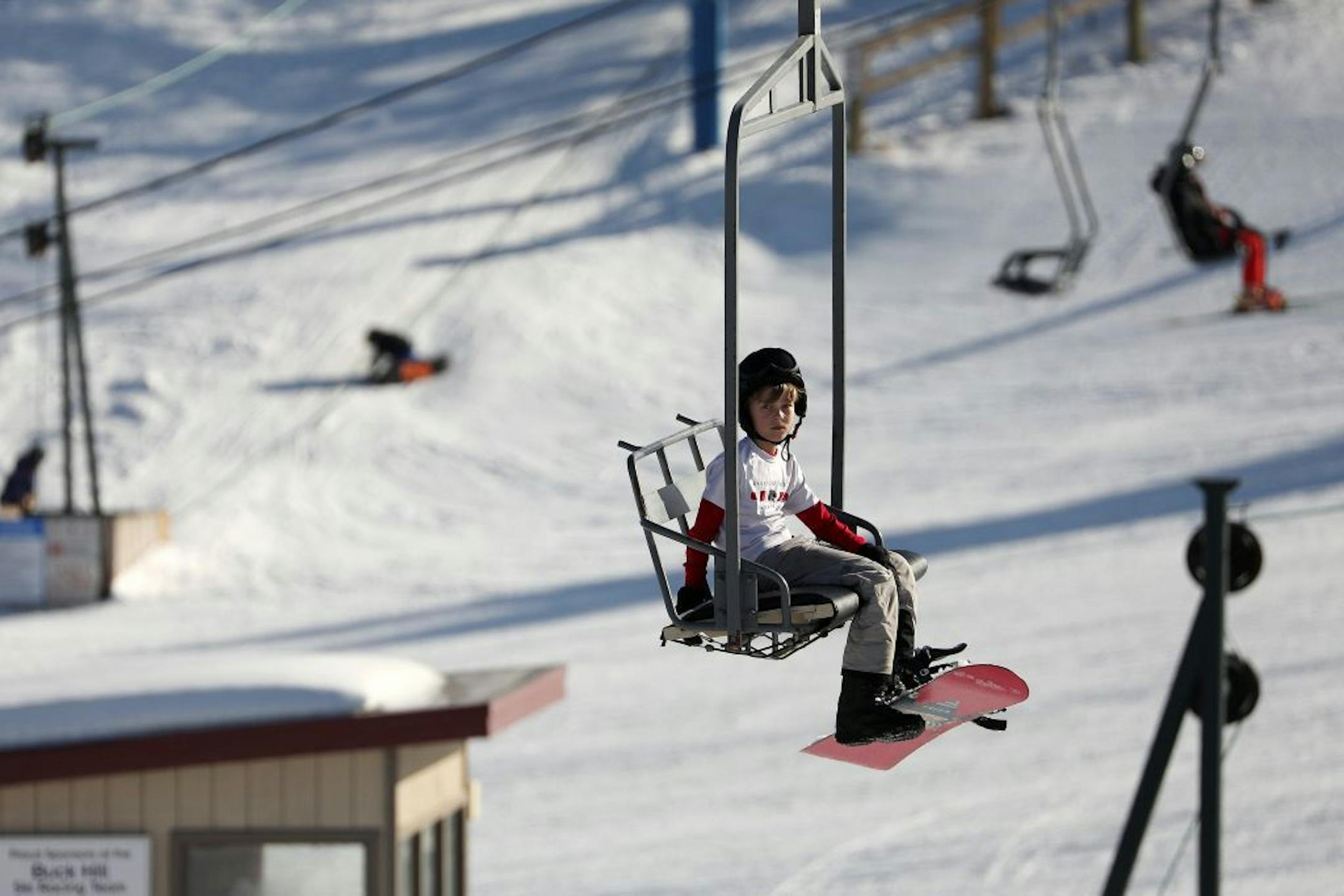 With only a long sleeve T-shirt, a young snowboarder rode the ski lift on an unusually warm day Friday.