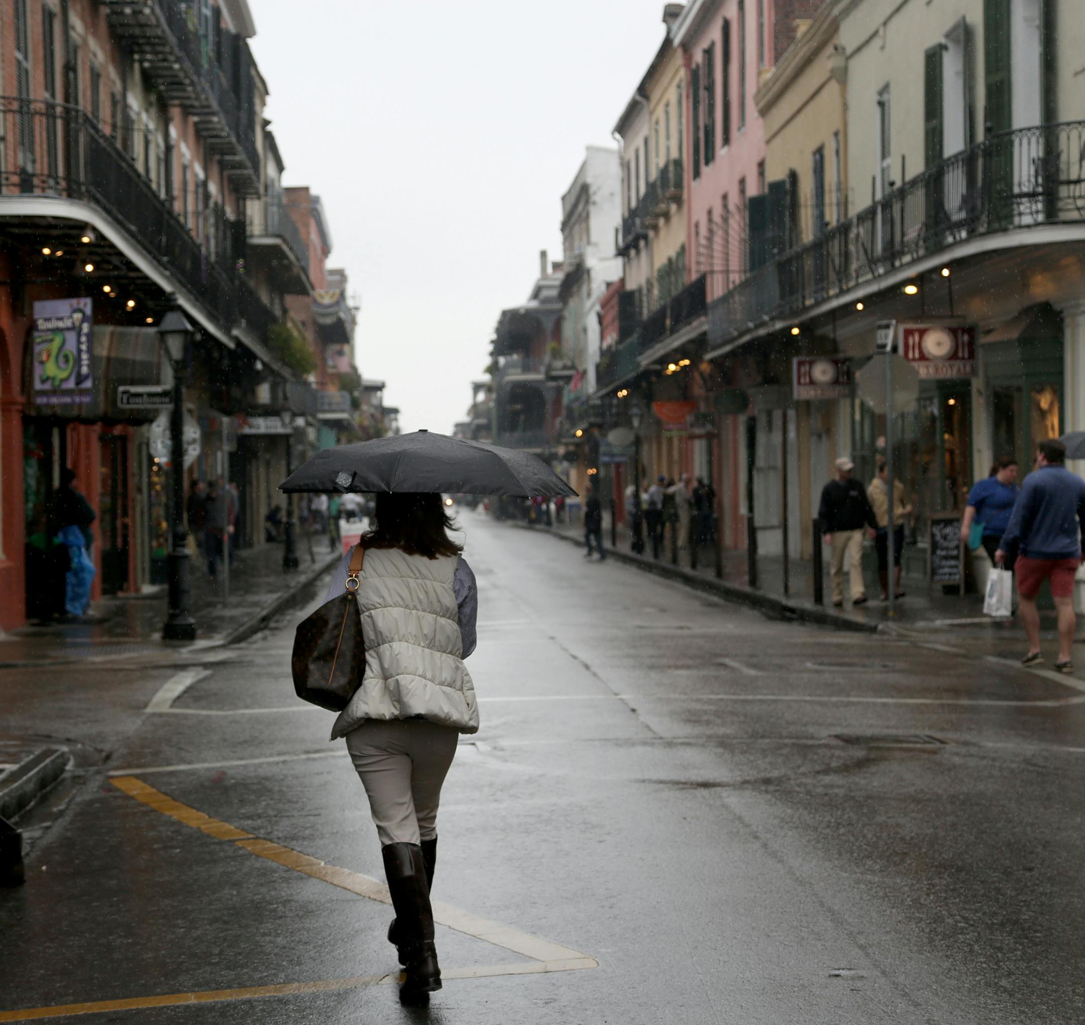 A pedestrian dealt with the rain walking in the French Quarter . ] (KYNDELL HARKNESS/STAR TRIBUNE) kyndell.harkness@startribune.com Travel story ten years later in New Orleans LA, Saturday, March 8, 2015.
