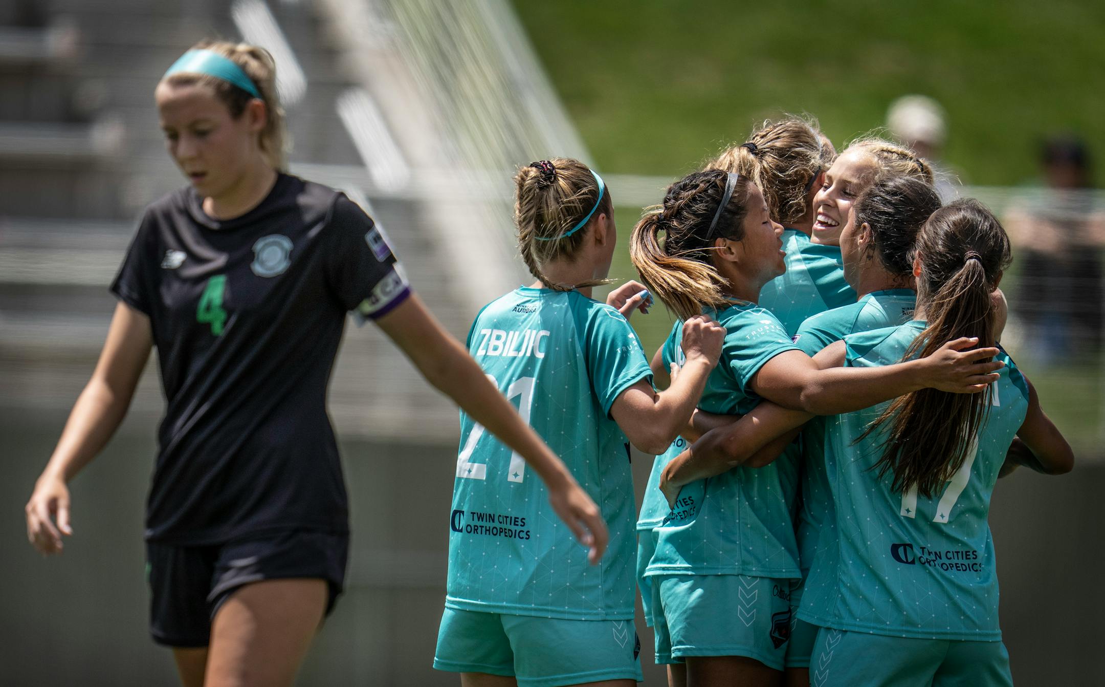 Riley Casey, of St. Louis, walked away as Morgan Stone, center, and Minnesota Aurora teammates celebrate her first half goal.