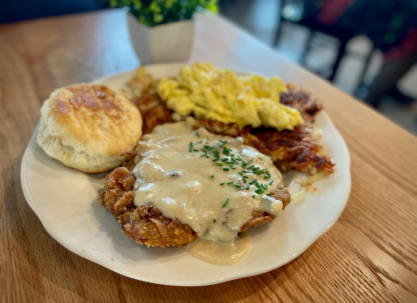 Country fried steak with peppery breakfast gravy dripping off the top, served with a biscuit, hashbrowns and some scrambled eggs.