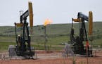 FILE -In this June 12, 2014 file photo, oil pumps and natural gas burn off in Watford City, N.D. Methane emissions will likely be the next big environ