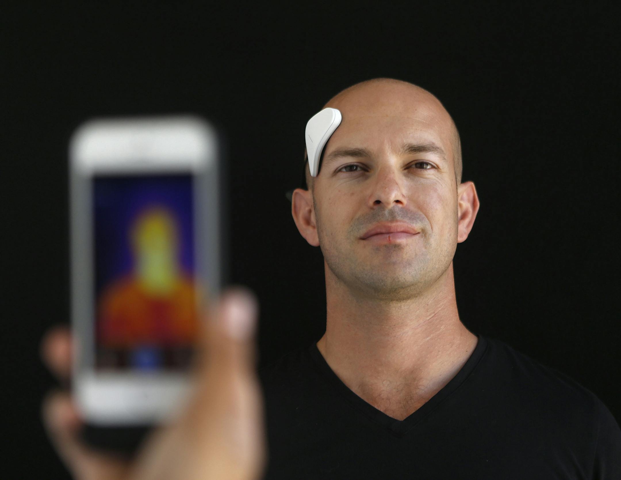 Dan Wetmore demonstrates the Thync, a bluetooth connected wearable device that sends electronic pulses to your cranial nerves to either make your calmer or more energized, depending on your preference, at Thync in Los Gatos, Calif., on June 1, 2015. Infrared photography can show how the device heats up areas of the face and neck. (Jim Gensheimer/Bay Area News Group/TNS) ORG XMIT: 1168960